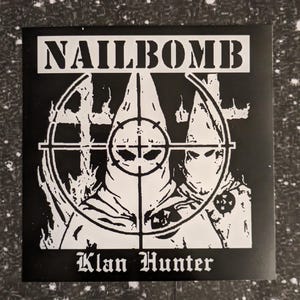 Könnte beinhalten: Schwarzweißes Bild eines Plattencovers mit dem Bandnamen "NAILBOMB" in großen weißen Buchstaben. Das Bild zeigt eine verhüllte Figur im Fadenkreuz mit dem Text "Klan Hunter" darunter.