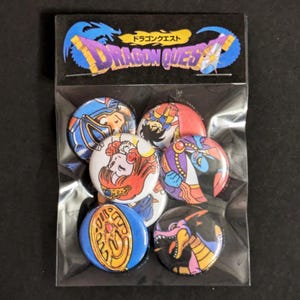 Puede incluir: Un conjunto de siete botones de solapa con temática de Dragon Quest. Los botones presentan varios personajes y símbolos de la popular serie de videojuegos. Los botones son redondos y tienen un acabado plateado brillante. Los botones están empaquetados en una bolsa de plástico transparente con una tarjeta de encabezado negra que dice "Dragon Quest" en japonés e inglés.