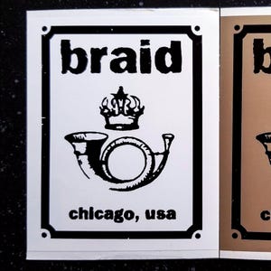May include: Black and white sticker with the word "braid" in bold letters, a crown, and a stylized image of a bugle. The text "chicago, usa" is below the image.