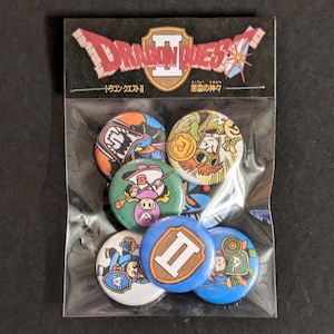 May include: A set of eight Dragon Quest II themed pinback buttons. The buttons feature various characters and imagery from the game, including a dragon, a knight, and a princess. The buttons are packaged in a clear plastic bag with a Dragon Quest II header card.