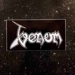 Może przedstawiać: Czarno-biała naklejka z napisem "Venom" w stylizowanym foncie.