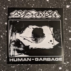 Puede incluir: Pegatina en blanco y negro con el texto "DISTORTION" en una fuente estilizada y en negrita. La pegatina presenta un gráfico de un ojo distorsionado con el texto "HUMAN=GARBAGE" debajo.