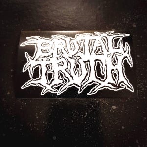 Puede incluir: Una pegatina en blanco y negro con el texto "BRUTAL TRUTH" en una fuente estilizada de heavy metal.