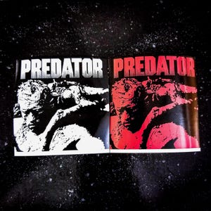 May include: Two black and white printed posters with the word "PREDATOR" in white letters on a black background. The posters feature a black and white image of a creature from the movie Predator.