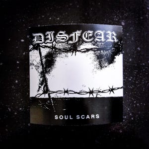 May include: A black and white sticker with the word "DISTFEAR" in a gothic font above a barbed wire design. The text "SOUL SCARS" is printed at the bottom. The sticker is rectangular in shape.
