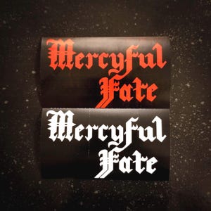 Puede incluir: Dos pegatinas negras y blancas con el texto "Mercyful Fate" en una fuente gótica. La pegatina superior tiene texto rojo y la pegatina inferior tiene texto blanco.