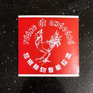 May include: Red square sticker with a white rooster illustration and the text "Tuong Ot Chocoboo" in a circle around the rooster. The text "辣椒 新 旨 醤" is below the rooster.