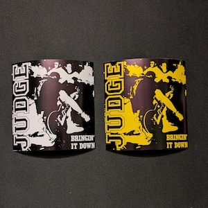 May include: Two black and white stickers with the word "JUDGE" in yellow letters. The stickers feature a black and white image of a person playing a guitar with the text "Bringin' It Down" below the image.