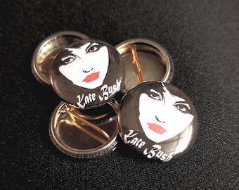 May include: Four black and white button badges featuring a portrait of Kate Bush and the text "Kate Bush" in white lettering.