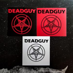 May include: Three square stickers displaying the word "DEADGUY" in bold, capital letters. Two stickers feature a red pentagram with a goat's head within a circle, one on a black background and one on red. The third sticker has a black pentagram on a white background.