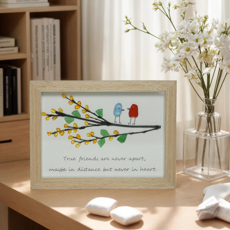 May include: A framed artwork featuring two birds made of colorful glass perched on a branch with yellow flowers. The quote "True friends are never apart, maybe in distance but never in heart." is written below the birds.