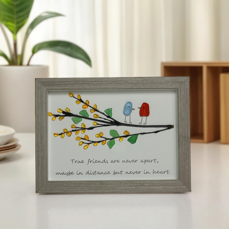 May include: A framed artwork featuring two glass birds perched on a branch with yellow flowers. The quote "True friends are never apart, maybe in distance but never in heart." is written below the birds.