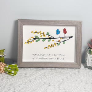 May include: A framed artwork featuring a branch with yellow and green glass beads, two birds made of blue and red glass, and the quote "Friendship isn't a big thing, it's a million little things".