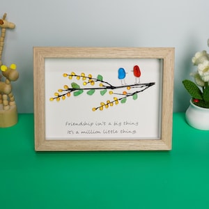 May include: Framed artwork featuring a branch with yellow and green glass beads, two birds made of glass beads, and the quote "Friendship isn't a big thing, it's a million little things".
