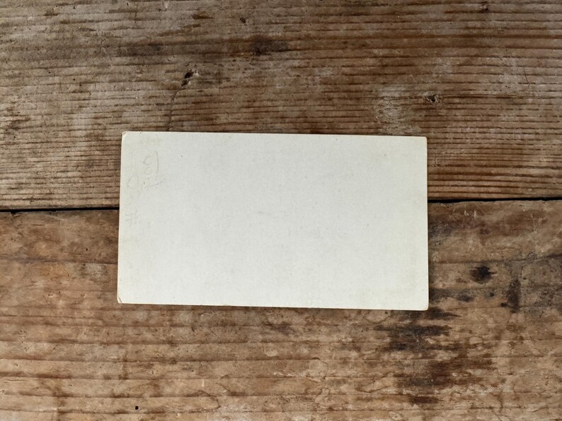 Puede incluir: Una tarjeta blanca en blanco con una tenue marca de l&aacute;piz en la esquina superior izquierda. La tarjeta est&aacute; sobre una superficie de madera.