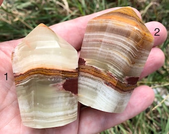 May include: Two green, white and brown banded onyx crystal points. The points are faceted and have a pointed top. The points are labelled 1 and 2.