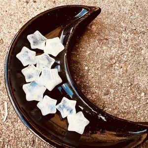 May include: A black crescent moon-shaped dish filled with white selenite crystal stars.