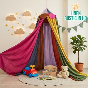 May include: A colorful play tent with a multi-colored canopy and flowing fabric in shades of pink, blue, brown, purple, yellow, and green. The scene includes a toy car, a wooden play kitchen, a teddy bear, and books, creating a playful atmosphere. The text "LINEN RUSTIC IN HB" is visible.