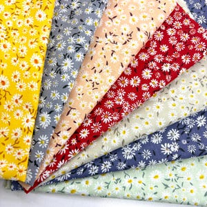 May include: A collection of daisy-patterned fabric in various colors, including yellow, gray, peach, red, and blue. The fabric features white daisies with yellow centers and green stems, suitable for sewing and crafting projects.