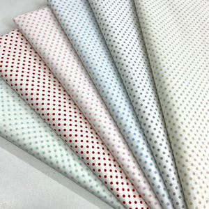 May include: A collection of folded fabric samples in various colors, each patterned with small polka dots. Colors include red, pink, blue, gray, and beige, all on a white background. The fabric appears to be cotton or a similar material.