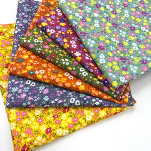 May include: A collection of floral fabric swatches in various colors, including yellow, orange, green, purple, and pink. Each fabric features a repeating pattern of small flowers, creating a vibrant and cheerful aesthetic. The fabrics are neatly arranged, showcasing the diverse color palette and floral designs.