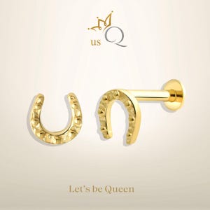 May include: A pair of gold horseshoe earrings. One earring is a stud with a horseshoe design, the other is a horseshoe hoop.
