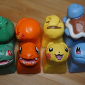 May include: Six small, hand-painted figurines of Pokemon characters. The characters are Bulbasaur, Charmander, Squirtle, Pikachu, and two forms of Squirtle.