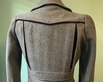 May include: A gray wool jacket with a black velvet trim and a cinched waist. The jacket has a unique design with a split back panel.