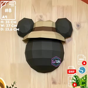 Puede incluir: Un modelo de papel 3D de Mickey Mouse con un sombrero safari marrón y beige. El modelo tiene 13,6 cm de profundidad, 37 cm de ancho y 35 cm de alto. El modelo está hecho de papel marrón y tiene una superficie texturizada.