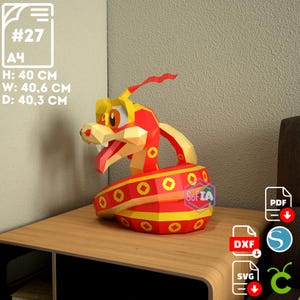 Puede incluir: Un modelo de papel de serpiente rojo y amarillo con la cola enroscada. El modelo mide 40 cm de alto, 40,6 cm de ancho y 40,3 cm de profundidad. El modelo est&aacute; sobre una mesa de madera. La imagen tambi&eacute;n incluye texto que dice "#27 A4 H: 40 CM W: 40.6 CM D: 40.3 CM" e iconos para archivos PDF, DXF y SVG.