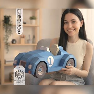 Puede incluir: Un modelo de papel low-poly de un coche de carreras azul con el número 1 en el lateral, un asiento de color claro y ruedas gris oscuro. El diseño incluye una etiqueta vertical con el texto SofIA e iconos de redes sociales, y una barra lateral.