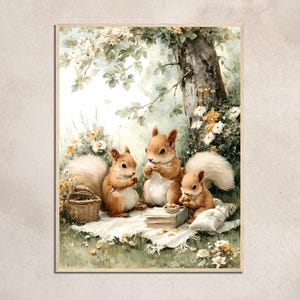 May include: Watercolor print of three squirrels having a picnic under a tree. The squirrels are brown with fluffy tails, gathered around a blanket with a basket and a book. The scene is set in a lush green meadow with flowers.