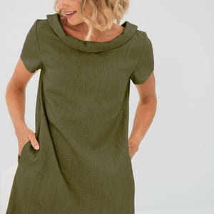 May include: A simple, olive green linen dress with a wide, folded collar and short sleeves. The dress has a relaxed fit and features two pockets on the front.