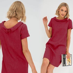 Può includere: Un abito di lino rosso a maniche corte, con un colletto largo e pieghettato e un dettaglio a fiocco sul retro.