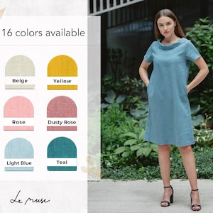 May include: A woman wearing a light blue linen dress with a scoop neck and short sleeves. The dress has pockets on the sides. The dress is available in 16 colors, including beige, yellow, rose, dusty rose, light blue, and teal. The text "Le muse" is visible at the bottom of the image.