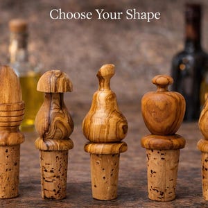 May include: Five wooden bottle stoppers in different shapes, such as a mushroom and a pear. Each stopper has a cork base and is made of light brown wood. The text "Choose Your Shape" is at the top.
