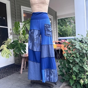 Könnte beinhalten: Weit geschnittene Hose mit hohem Bund und Patchwork-Design in verschiedenen Blautönen. Das Kleidungsstück besteht aus Einsätzen aus einfarbigem blauem Stoff, denimartigem Material und einem blauen Tarnmuster sowie einer Cargotasche an der Hüfte.