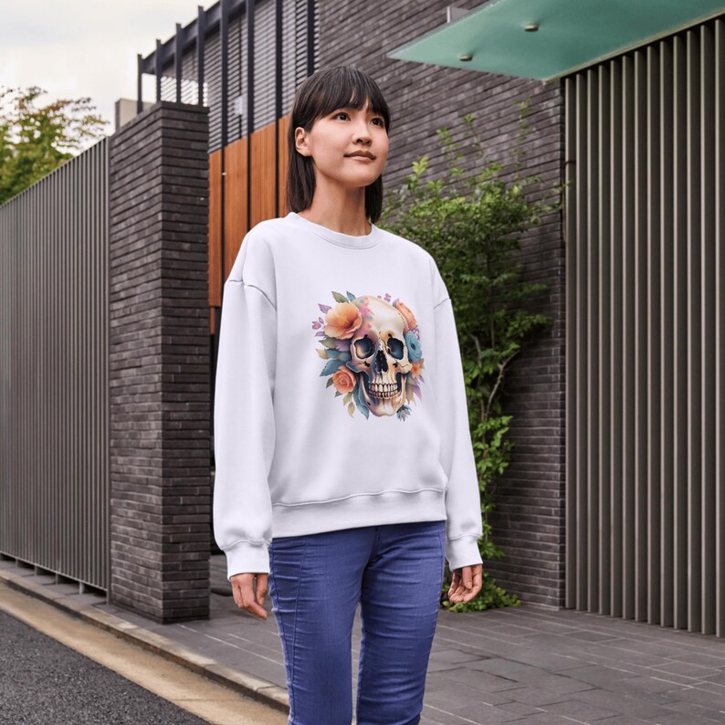 Puede incluir: Sudadera blanca con un gr&aacute;fico de calavera floral colorido. La calavera est&aacute; rodeada de flores rosas, naranjas y azules.