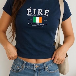 May include: A navy blue t-shirt with a white graphic of the Irish flag and the text "&Eacute;IRE Poblacht na h&Eacute;ireann Est. 1922 Baile &Aacute;tha Cliath 53.3408&deg; N, 6.2603&deg; W"