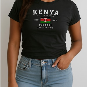 May include: Black t-shirt with a white graphic design featuring the text "KENYA", "REPUBLIC OF KENYA", "EST. 1963", "NAIROBI", and "1.2921&deg; S, 36.8219&deg; E". The graphic also includes the flag of Kenya.