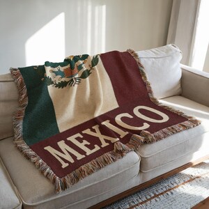 May include: A woven throw blanket featuring the flag of Mexico. The blanket displays the Mexican flag's green, white, and red colors, with the word "MEXICO" in large white letters. The blanket has a fringed edge.