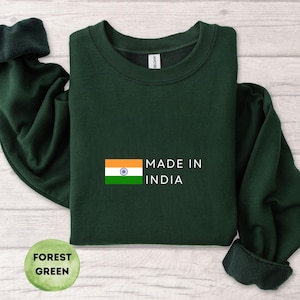 以下が含まれることがあります： 「MADE IN INDIA」の文字とインドの国旗がプリントされたフォレストグリーンのスウェットシャツ。スウェットシャツは無地で、クルーネックです。画像は真上から撮影されています。