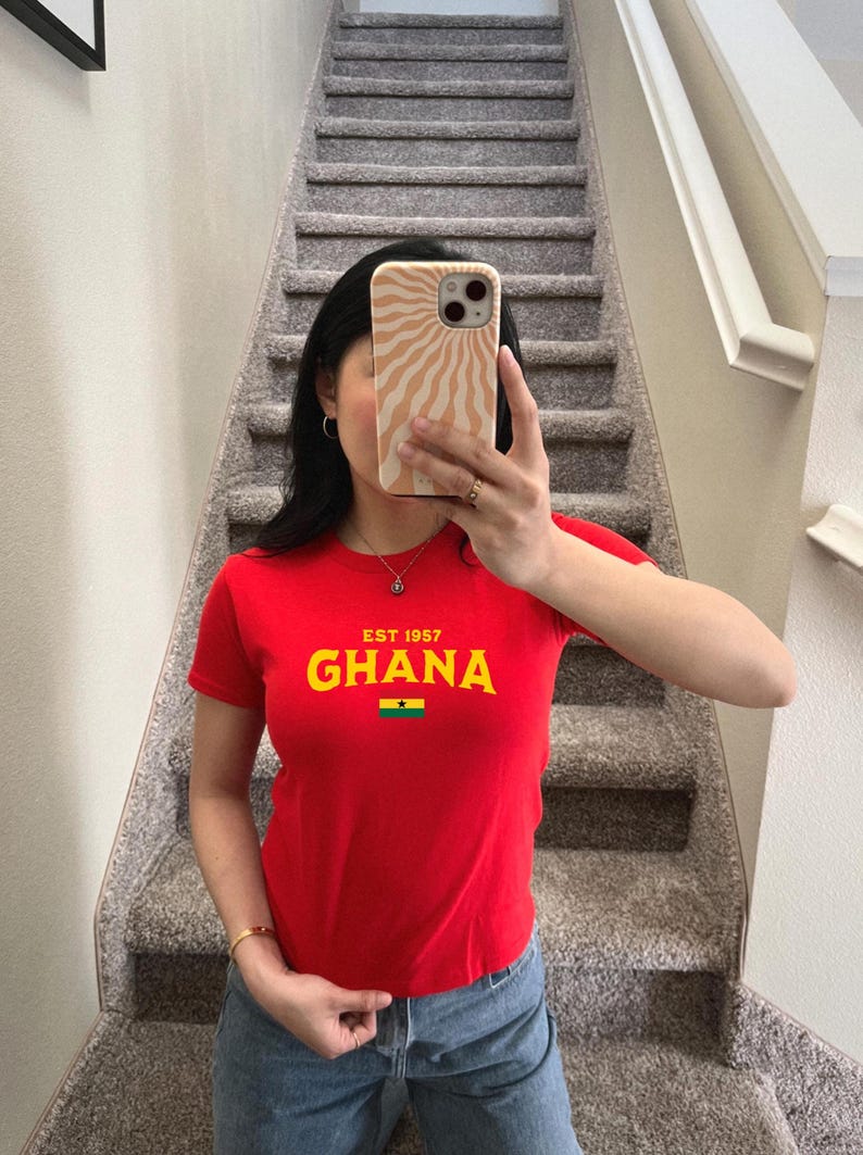 May include: Red t-shirt with a yellow graphic that says "EST 1957 GHANA" and a small Ghanaian flag.