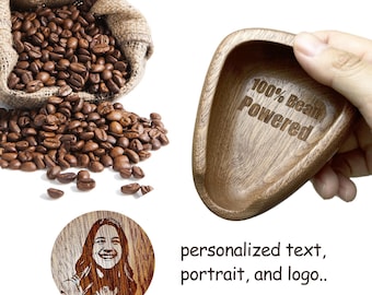May include: A wooden bowl with the text "100% Bean Powered" engraved on it. The bowl is made of dark wood and has a smooth, rounded shape. The bowl is being held by a hand.