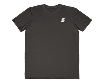 May include: Dark gray t-shirt with a small white logo on the upper left chest. The logo is a stylized letter "F" with a horizontal line above it. The shirt has short sleeves and a crew neck.