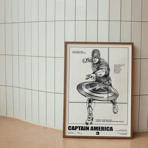 May include: A framed poster featuring a black and white illustration of Captain America throwing his shield. The poster has the text "I'm just a kid from Brooklyn" and "The price of freedom is high, but it's a price I'm willing to pay."