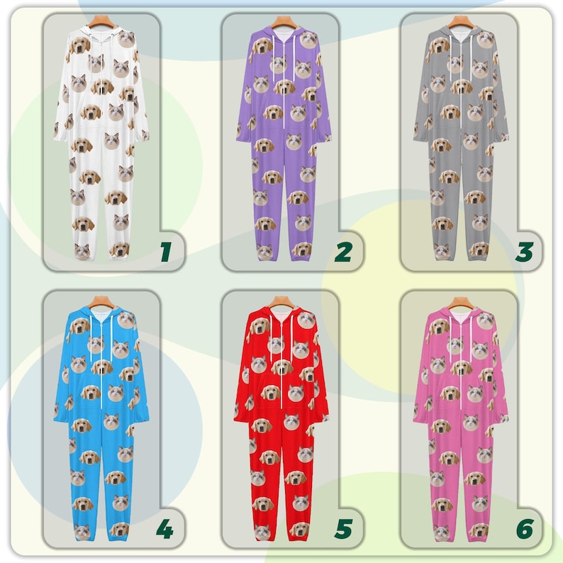 May include: Six hooded onesie pajamas in various colors: white, purple, gray, blue, red, and pink. Each onesie features a repeating pattern of dog and cat faces. The pajamas are displayed on wooden hangers.