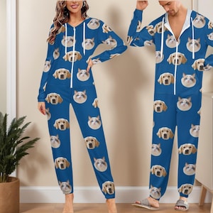 May include: Blue jumpsuit with a repeating pattern of dog and cat faces. The jumpsuit has a hood and a zipper down the front. The long-sleeved jumpsuit is made of a soft material and is suitable for lounging or sleeping.
