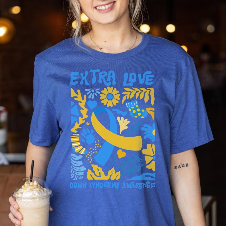A unisex short-sleeve T-shirt featuring the phrase “Extra Love” and a heart or ribbon design inspired by Down Syndrome Awareness. The shirt represents the 3:21 chromosome pattern and supports T21 moms, dads, and families. Made from soft cotton with a classic fit, ideal for awareness walks or casual wear.