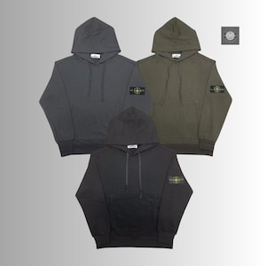 以下が含まれることがあります： グレーとオリーブグリーンの3色のフード付きスウェットシャツ。各スウェットシャツにはフロントポケット、ドローストリングフード、左袖にパッチが付いています。スウェットシャツは、明るい灰色の背景に表示されています。